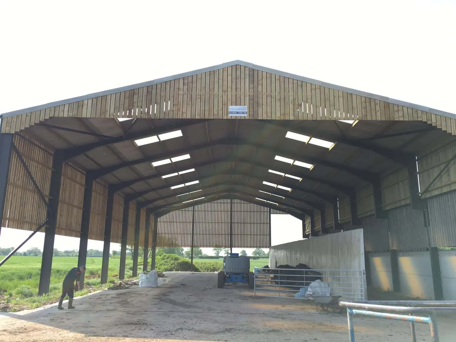 Interior of a wide open-sided barn showing roof lights along the ridge and a clear span structure