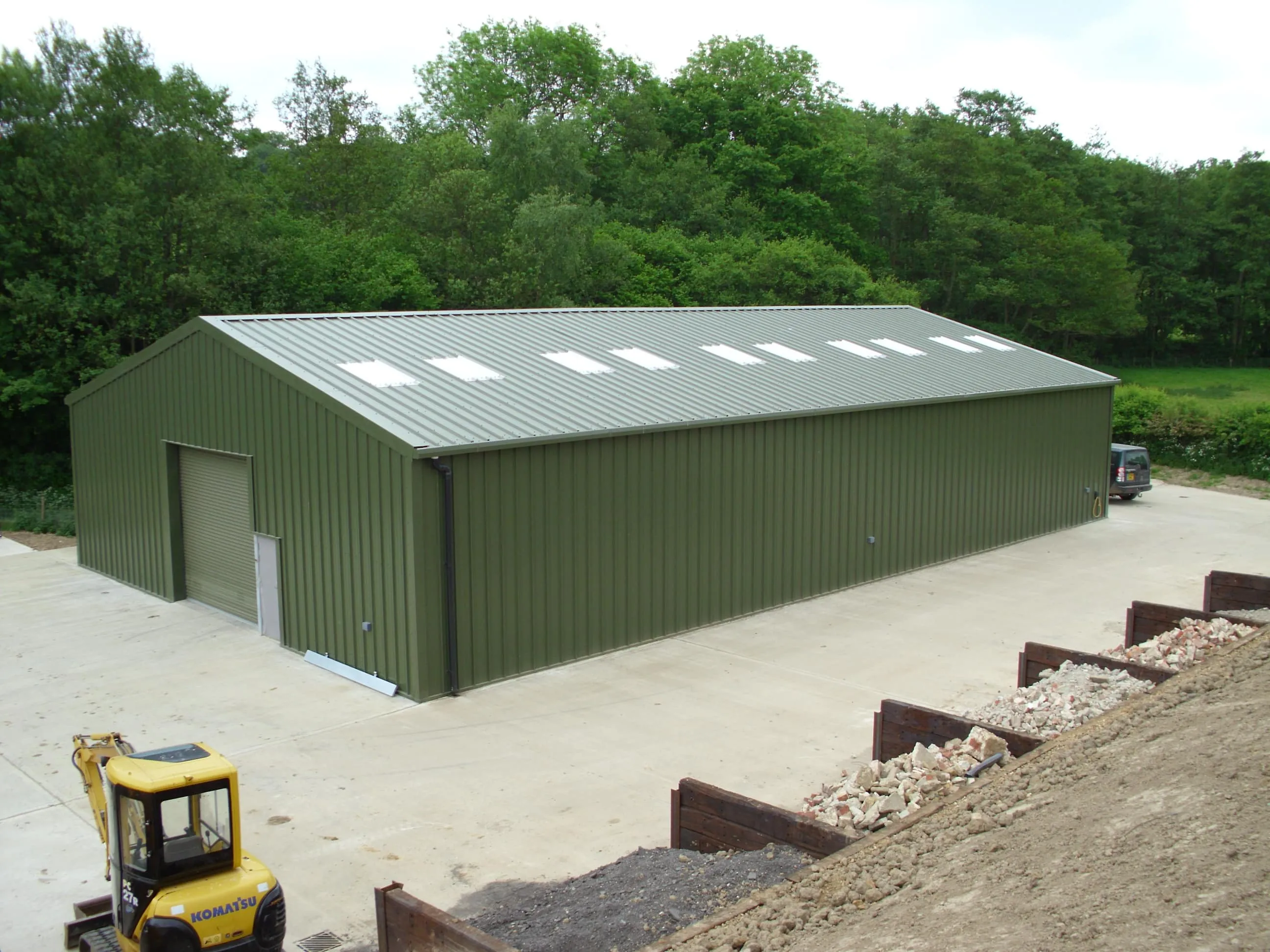 Compact green clad agricultural building with a concrete apron and hardcore surround