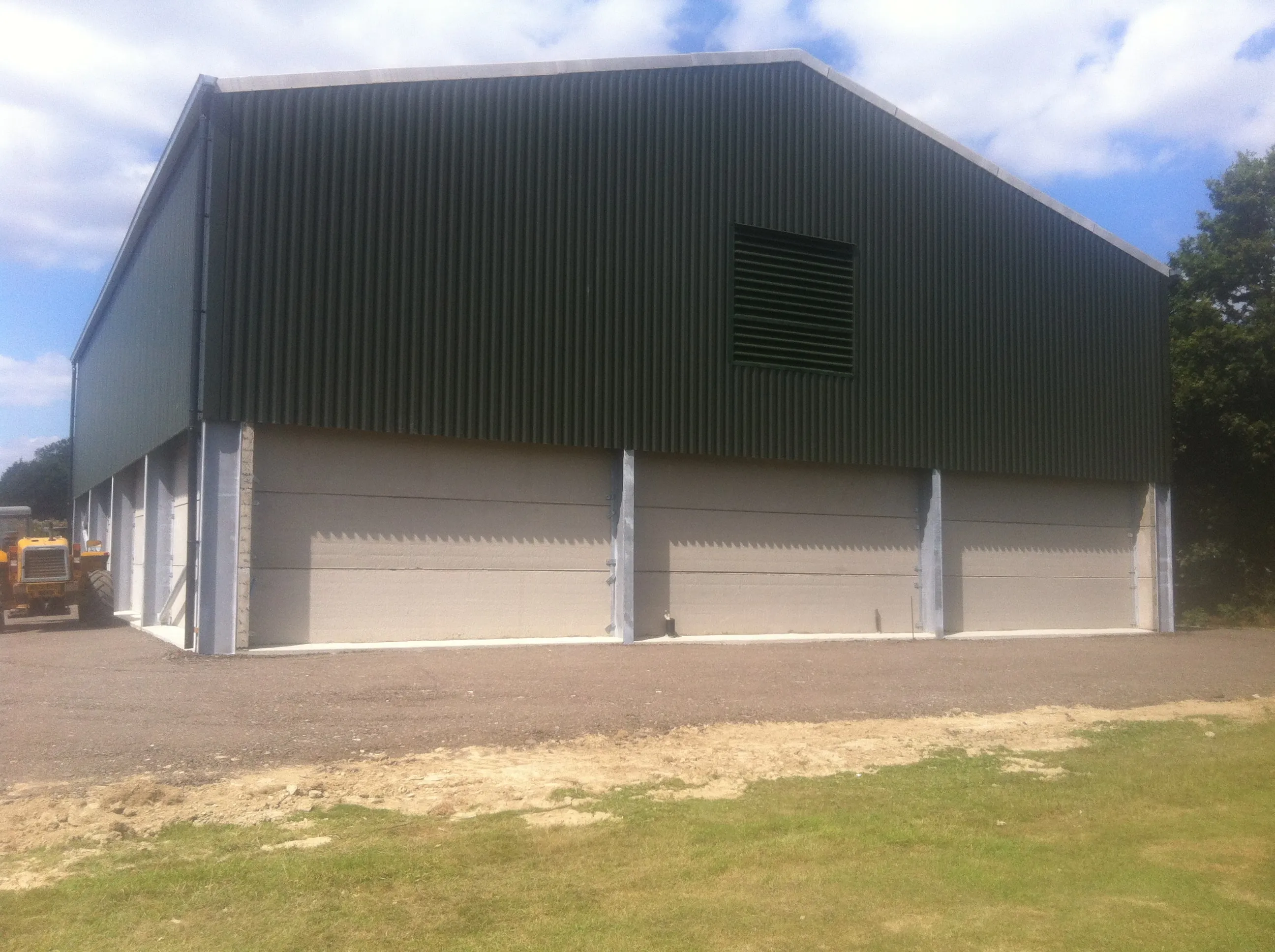 Dark green clad industrial unit with pale roller shutter doors and a finished concrete apron