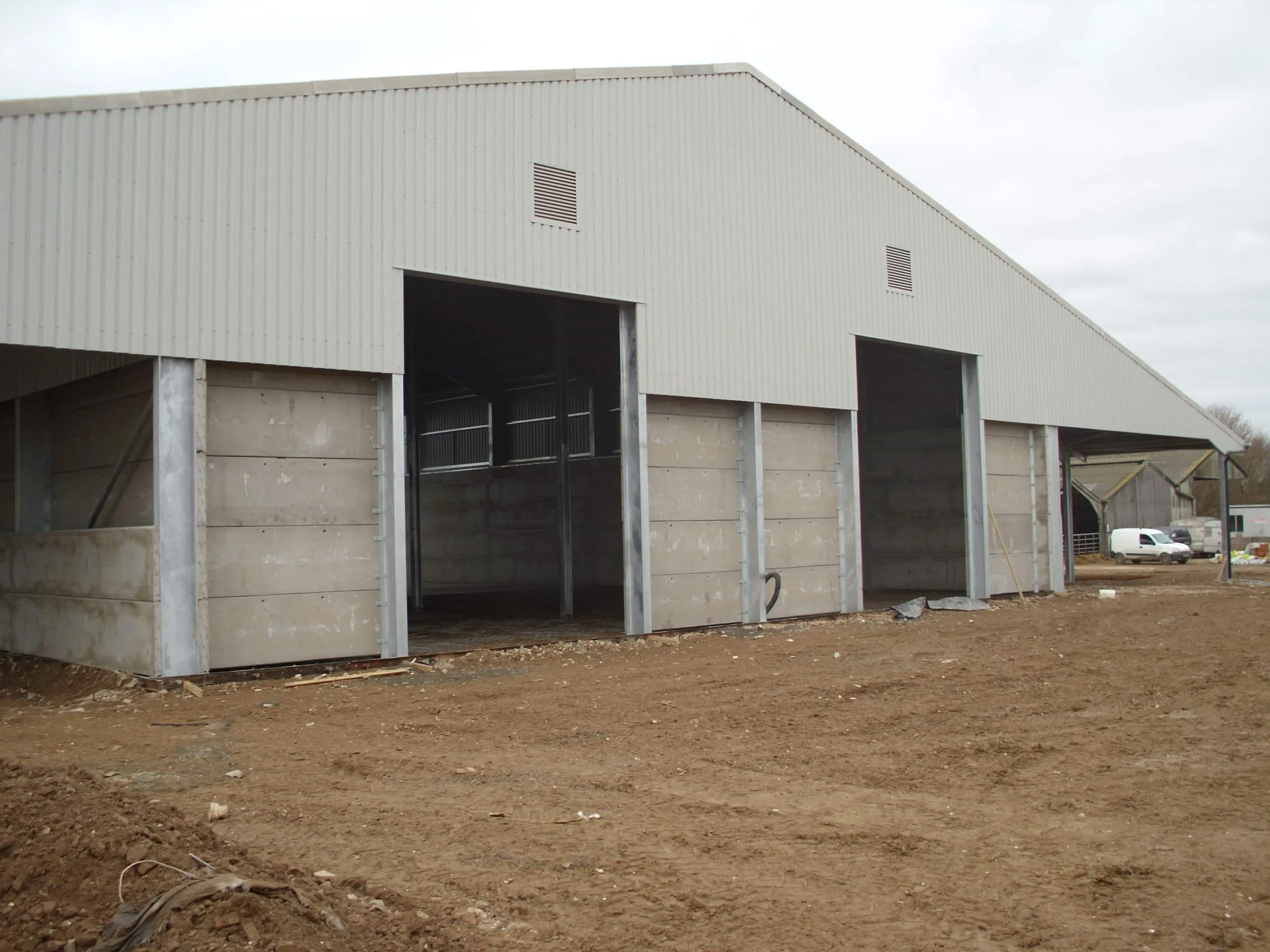 Completed steel-framed farm building with precast concrete panel walls and wide access openings