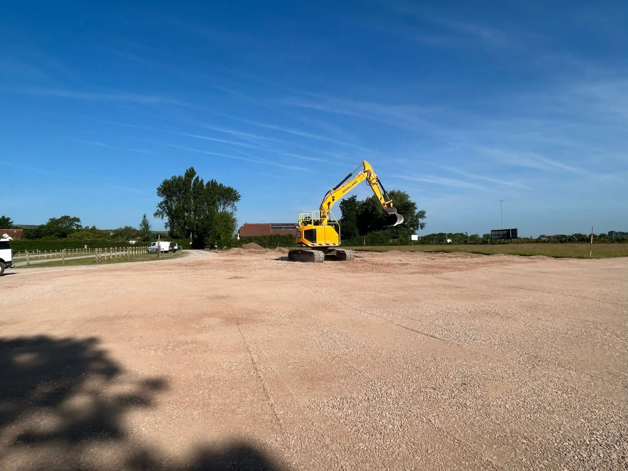 Wide view of a Woollard excavator working across a large levelled earthworks site