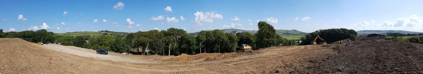 Large-scale earthworks in progress on a South Downs hillside, with dozers shaping graded ground