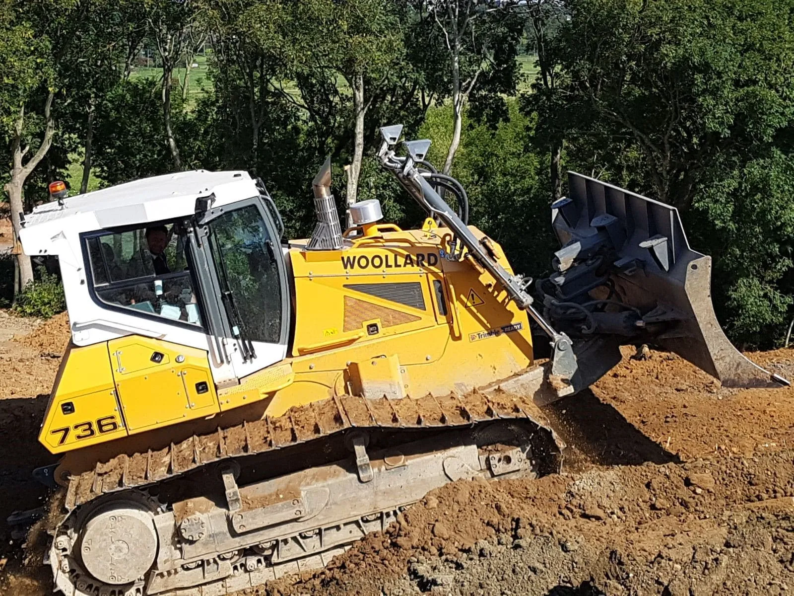 Woollard-liveried bulldozer standing on freshly graded ground at an earthworks site
